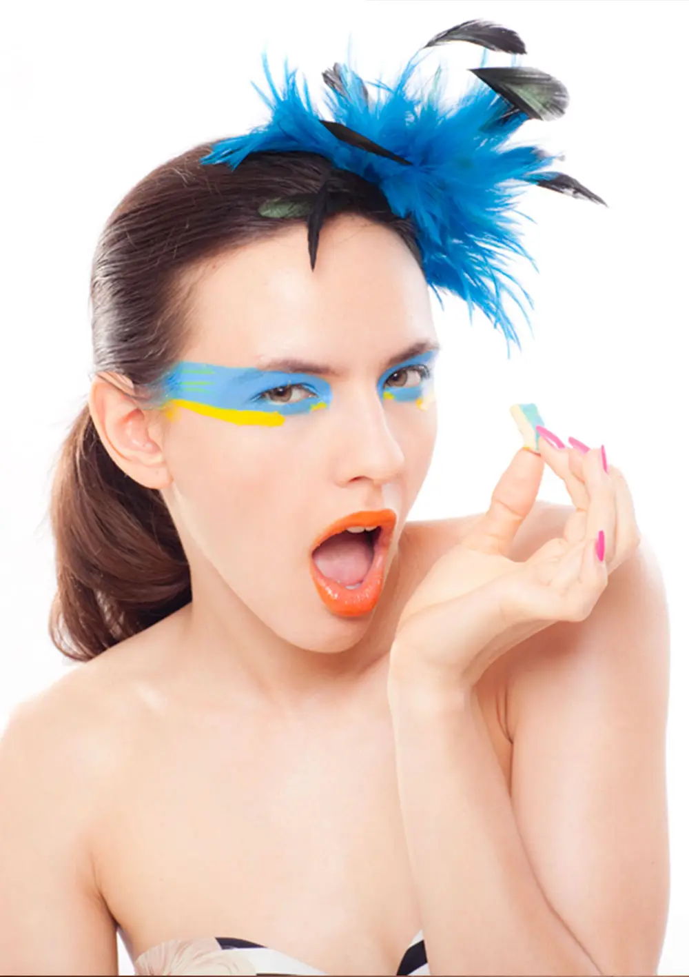 Model with blue feathers and bold eye make-up from a Studio White beauty campaign