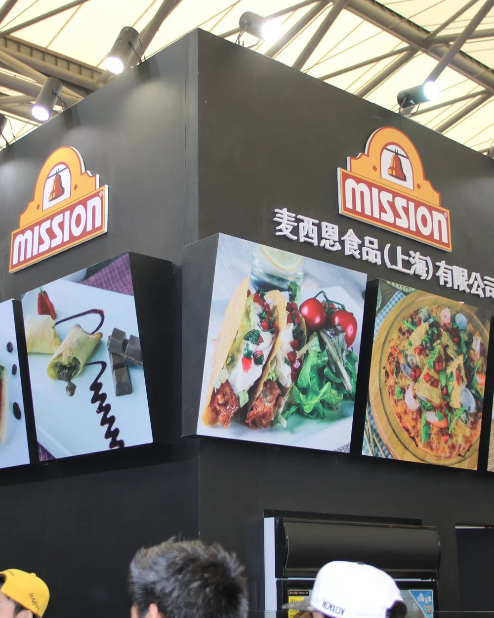 Corner tower of a Mission Foods exhibition stand with the illuminated Mission logo and backlit food lightboxes