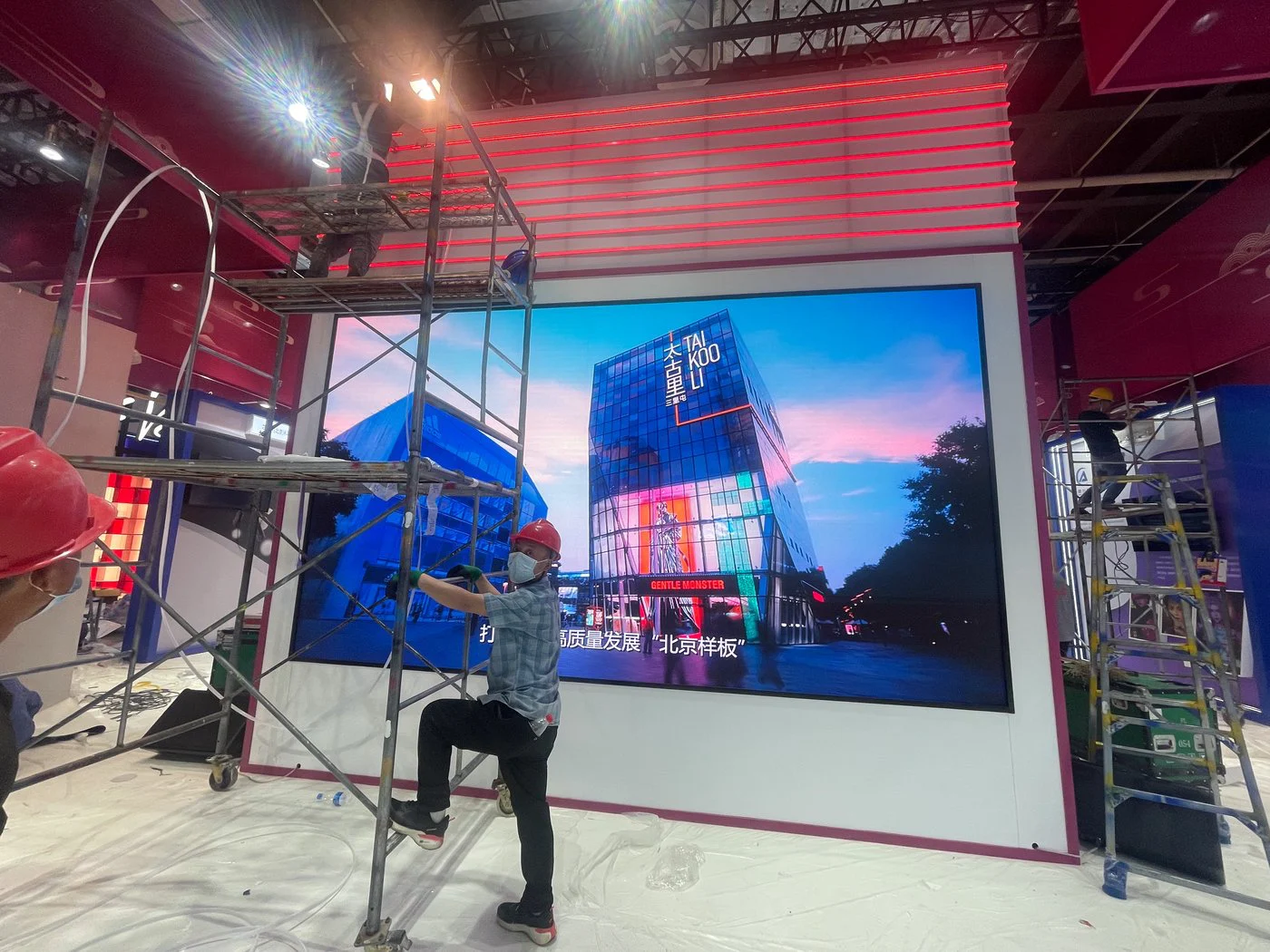 Technicians on scaffolding installing an LED wall in the Beijing pavilion