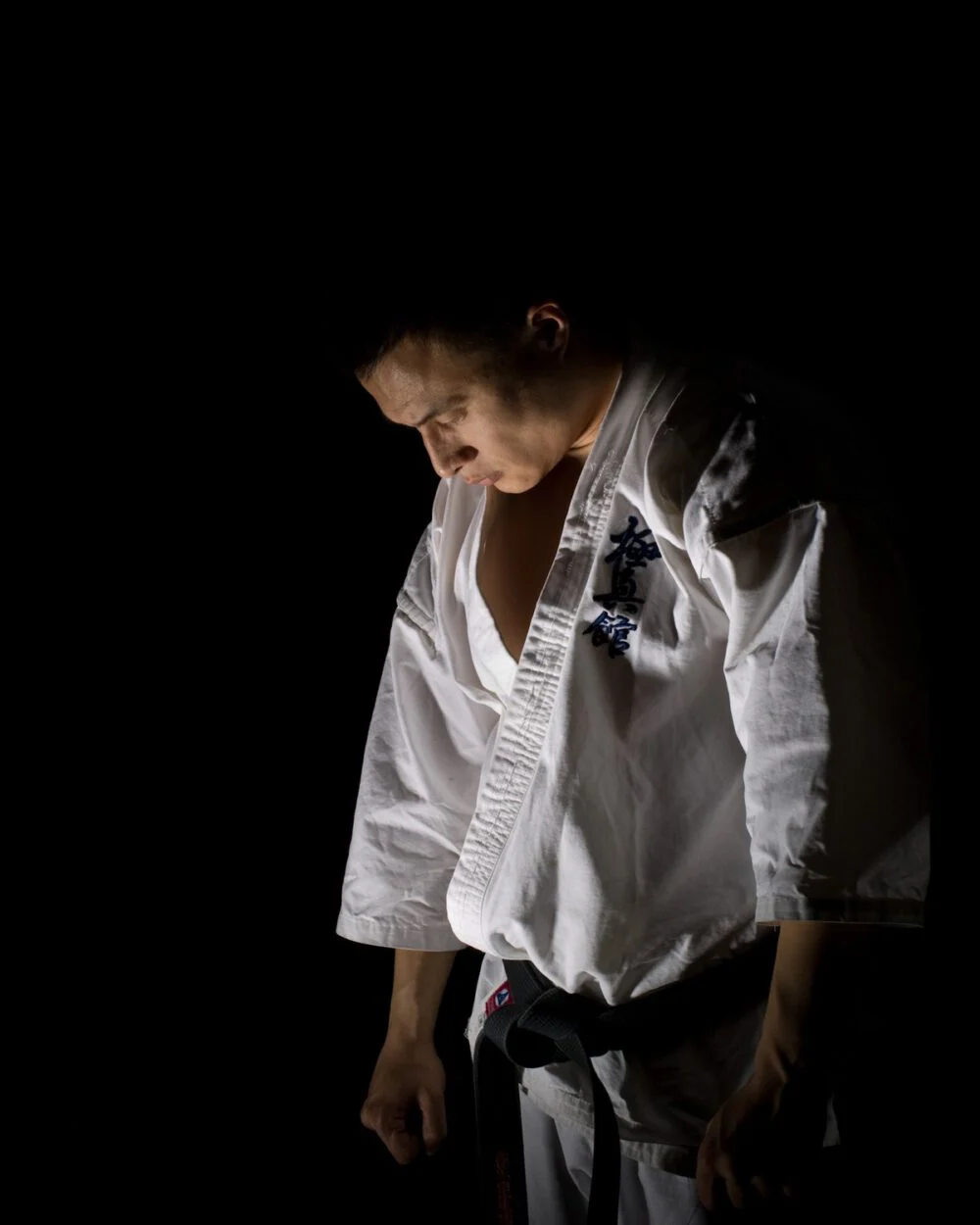 A Kungfuand master in a white uniform and black belt, head bowed in a calm moment