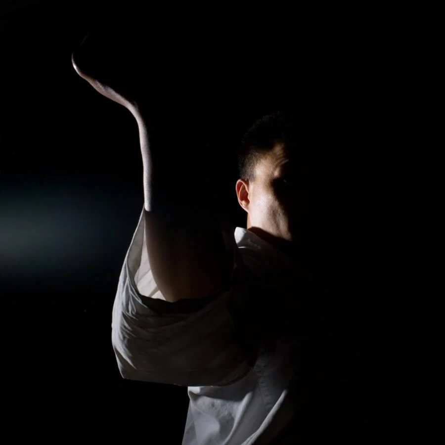 A side kick emerging from darkness, lit from behind